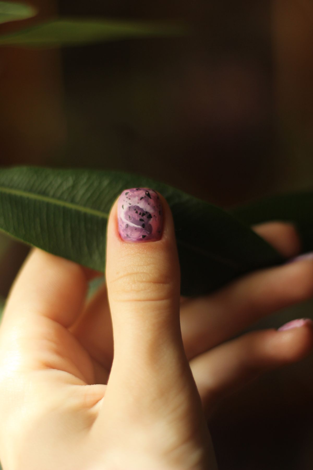 Purple nail art with a botanical detail